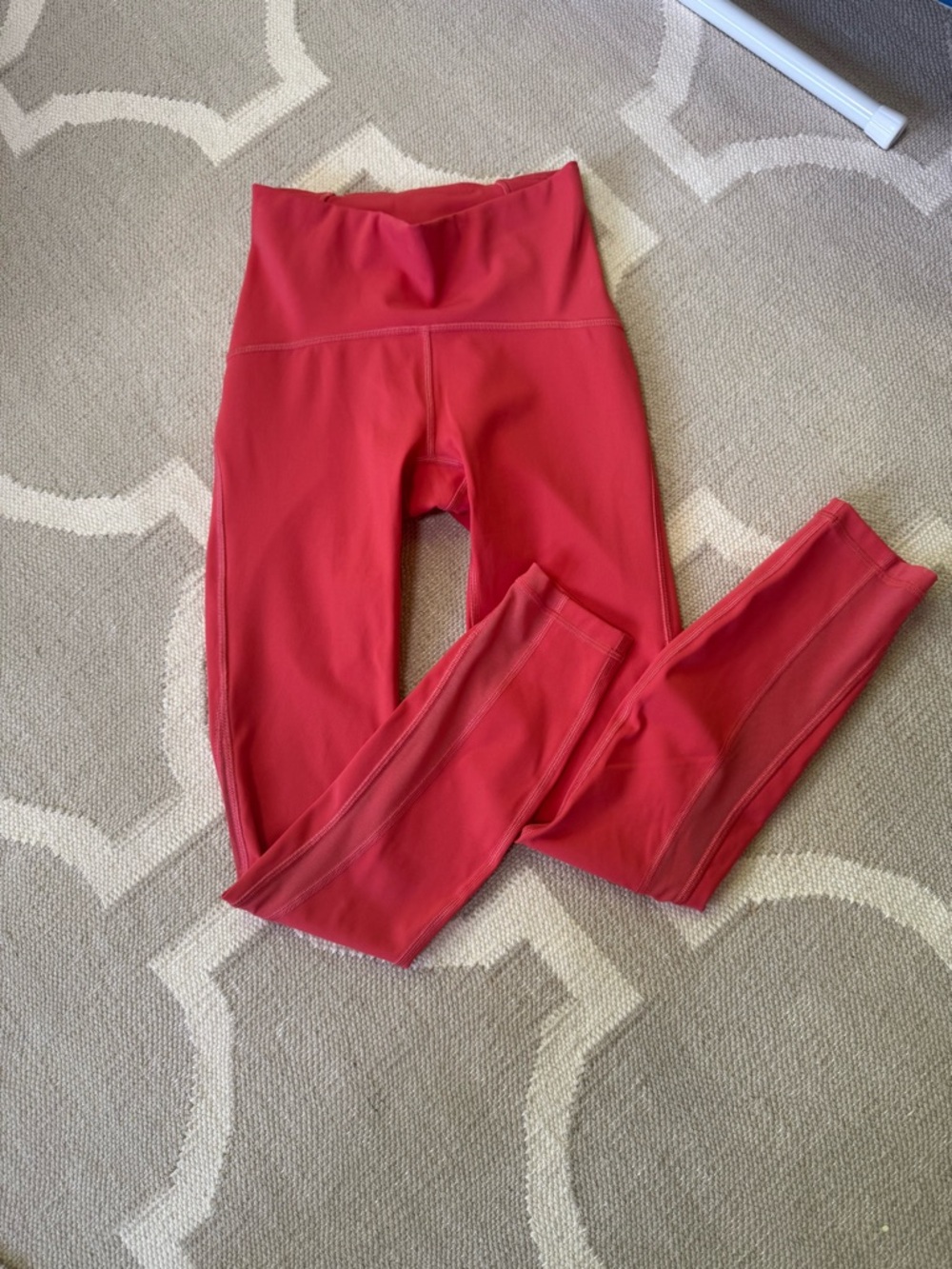 Lululemon Raspberry colored Athletic Leggings with net fabric around bottom leg.